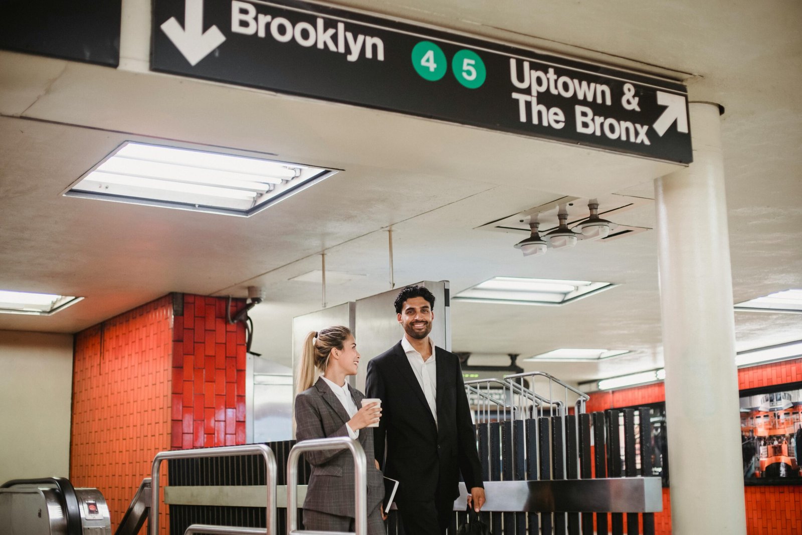 Business people in formal attire at a New York subway station, smiling and conversing.